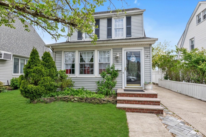 Charming WP Chalet Colonial Light gray siding exterior with black shutters and a front entry door with a full-view glass insert