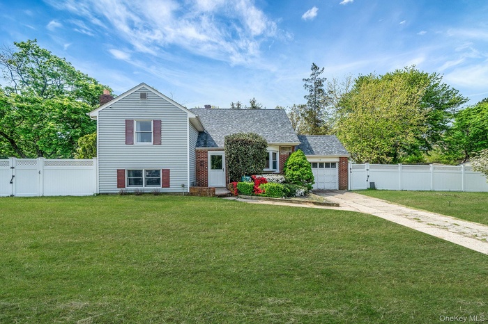 Split level-style home featuring a mixed facade of siding and brick, a single-car garage, and a manicured front lawn