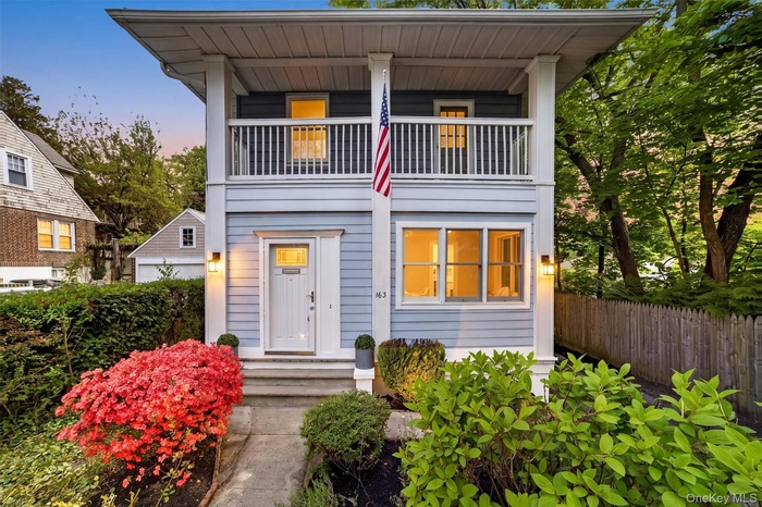 Two-story facade with light blue siding, white trim, and a second-story balcony