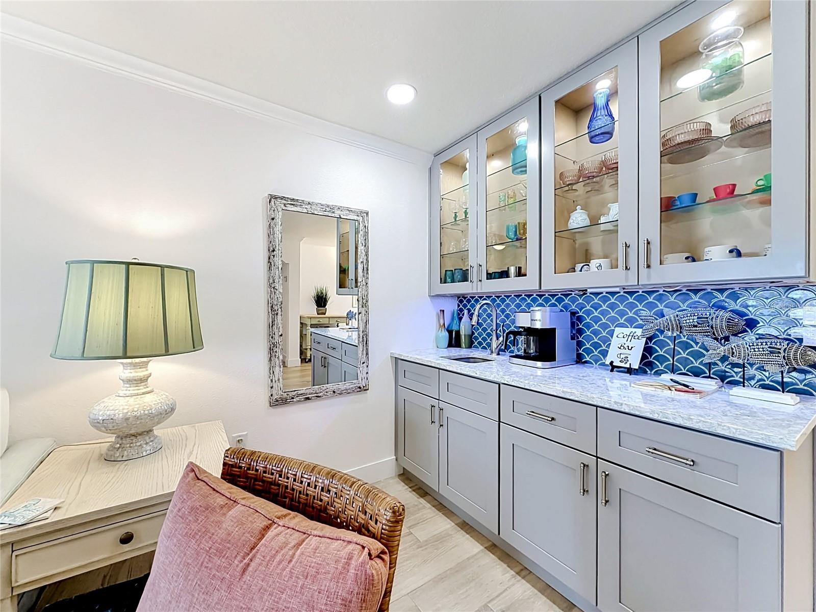 Wet bar and coffee bar with a beautiful backsplash, quartz countertop and glass cabinets with inside lights for added ambiance