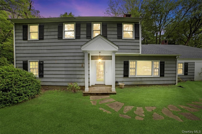 View of front of house with a chimney and a lawn