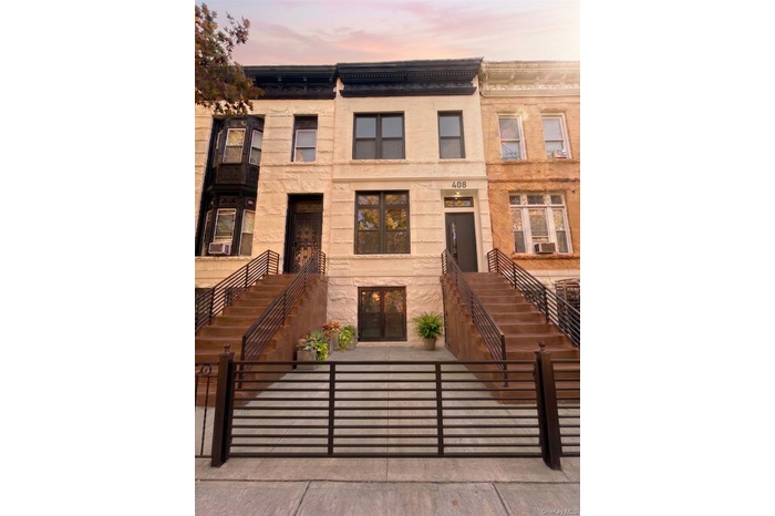 Stone facade townhouse featuring a black main entry door, dark-framed windows, and wrought iron railings