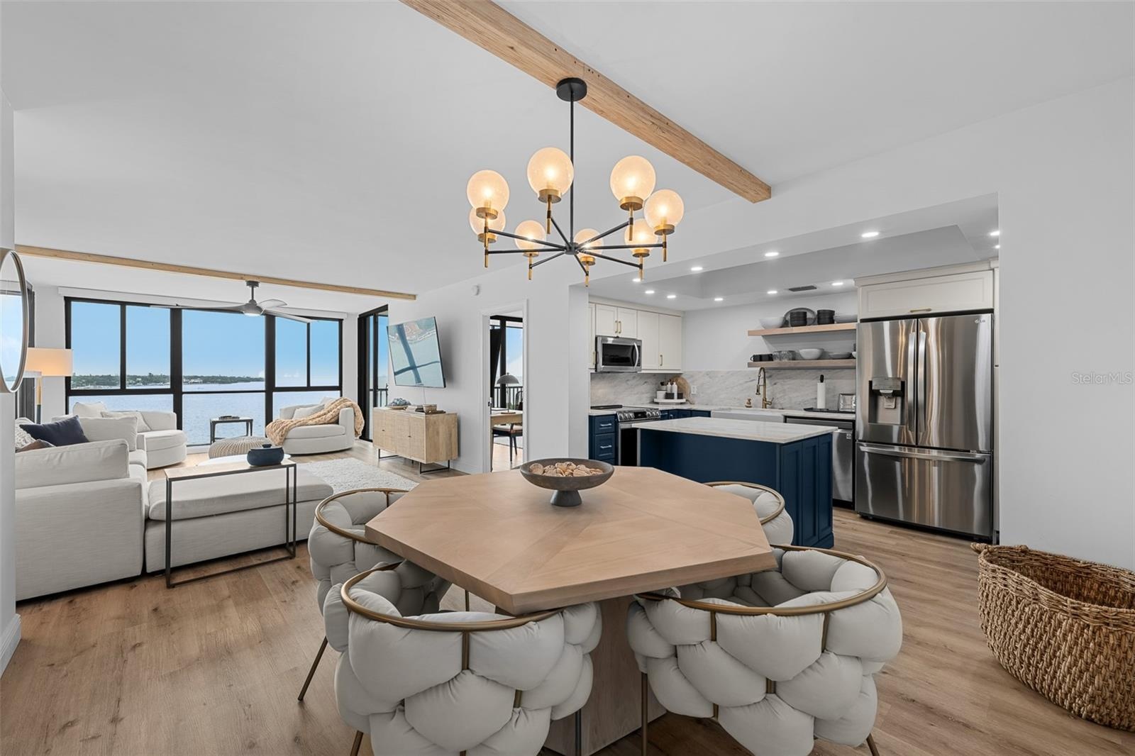 Open-concept great room with engineered hardwood flooring, exposed wood ceiling beam, and seamless flow to the dining area.