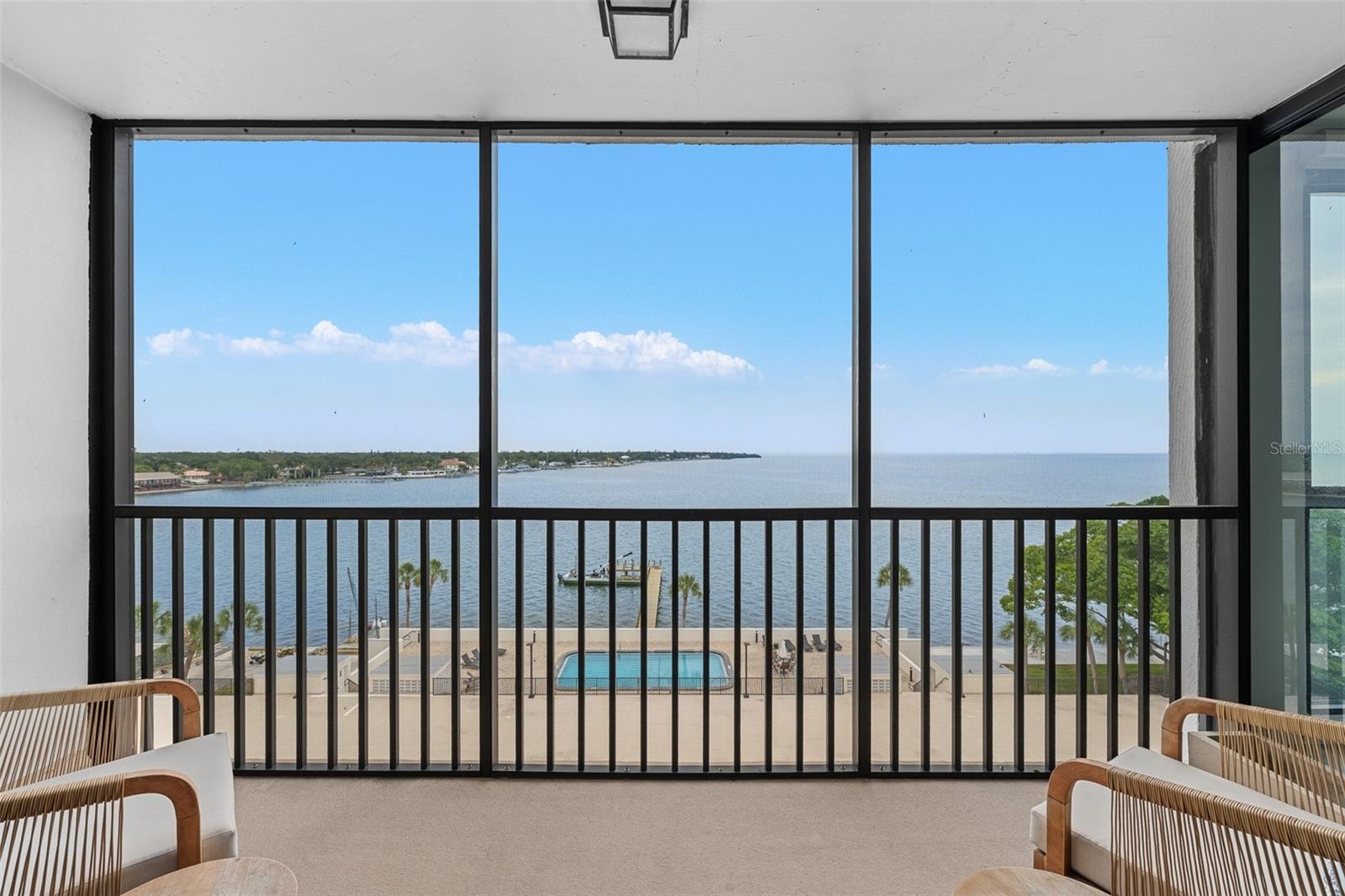Screened terrace overlooking the bay-side heated community pool, private fishing pier, and open water of Tampa Bay.