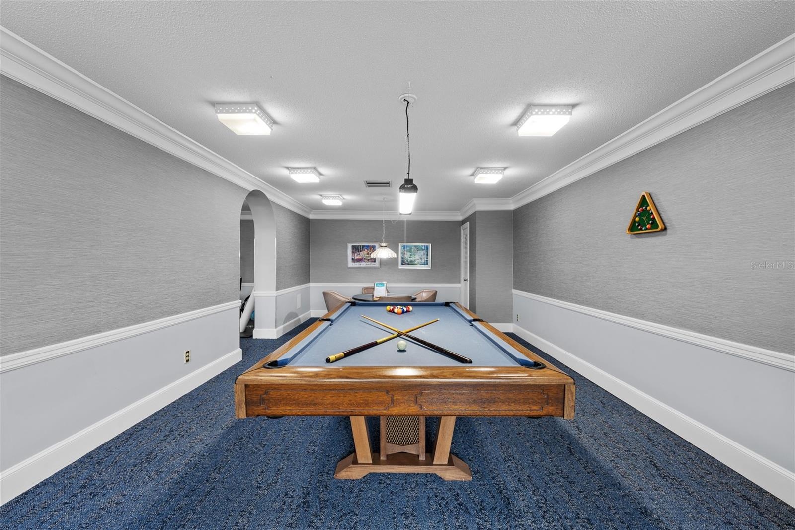 Community game room with a regulation billiards table, lounge seating, and arched architectural details.