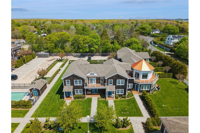 Shingle-style residences with a distinctive turret feature a private swimming pool, manicured lawns, paver walkways, and ample parking