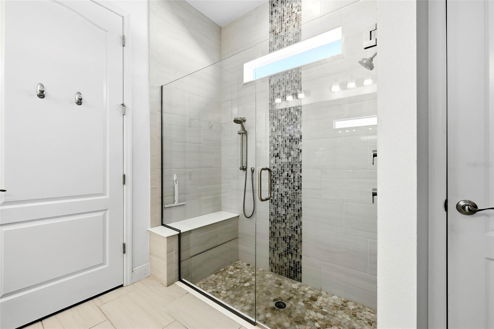 Frameless double-head shower with a built-in bench—spacious, stylish, and spa-inspired.