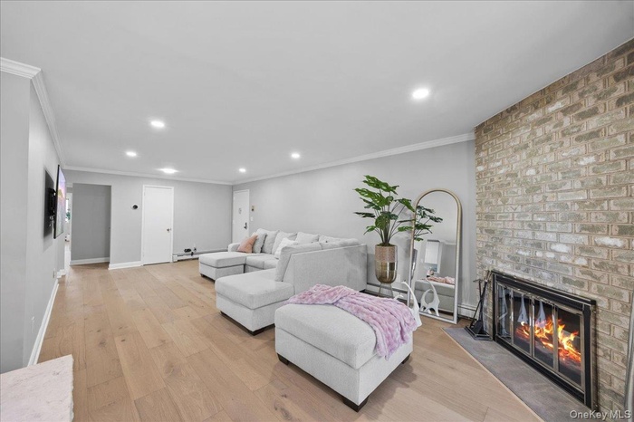 Living area featuring light-toned wood-finish flooring, recessed lighting, and crown molding