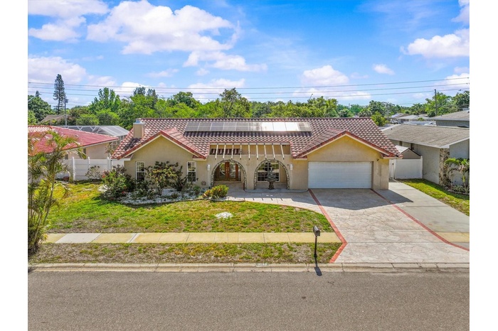 Aerial perspective highlights the home’s modern solar tile roof and prime Dunedin location—just minutes from vibrant downtown, waterfront parks, and t