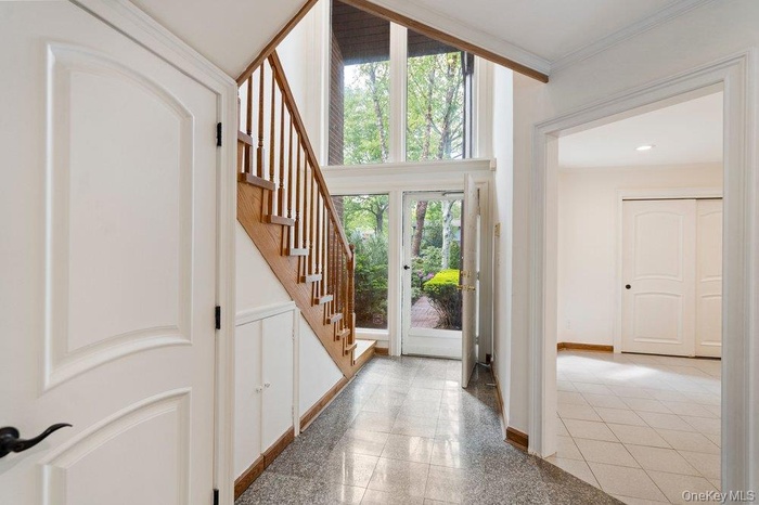 Foyer featuring a grand staircase with wood treads and railings, expansive floor-to-ceiling windows, and a tiled floor