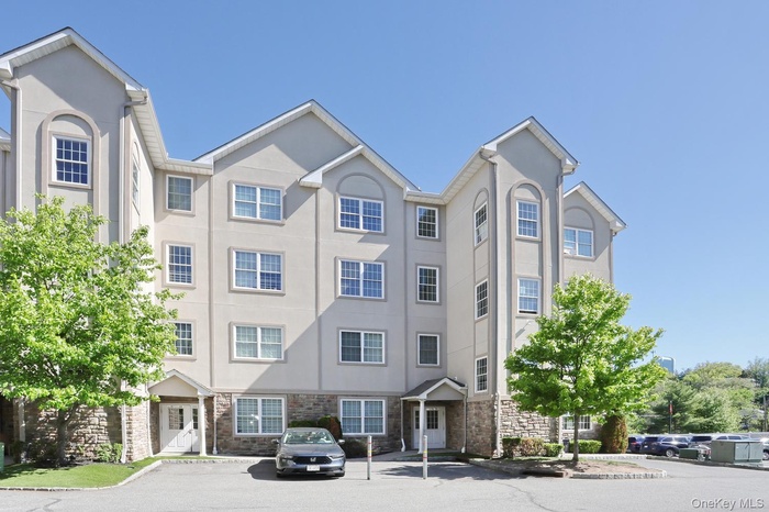 Multi-story building featuring a stucco exterior with stone veneer accents on the lower level