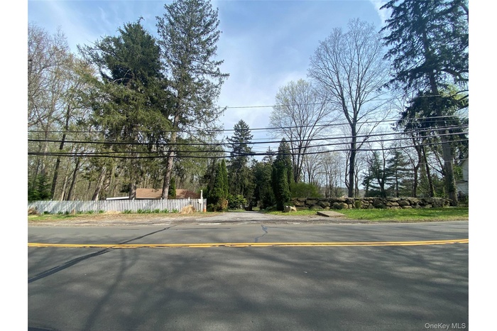 Private lot featuring mature trees, a natural stone retaining wall, and a white picket fence