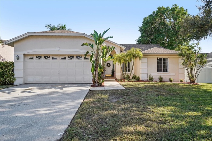 Front Exterior – This well-maintained single-story home features a welcoming façade with a two-car garage, mature tropical landscaping, and a clean co