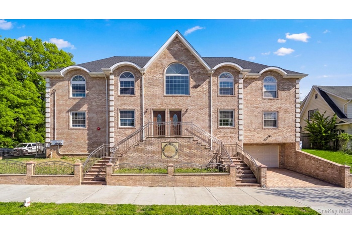 Brick facade residence featuring arched windows and multiple entryways