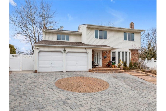 Traditional-style house featuring brick siding, curved driveway, a chimney, a gate, and fence