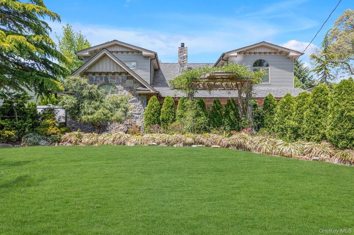 Beautiful curb appeal stone and siding exterior, featuring a stone chimney and decorative pergola