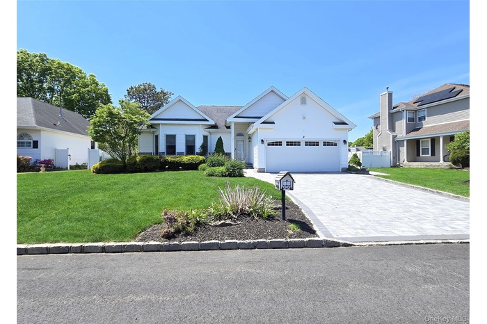 Ranch-style residence featuring a white exterior, a paver driveway, and a two-car garage