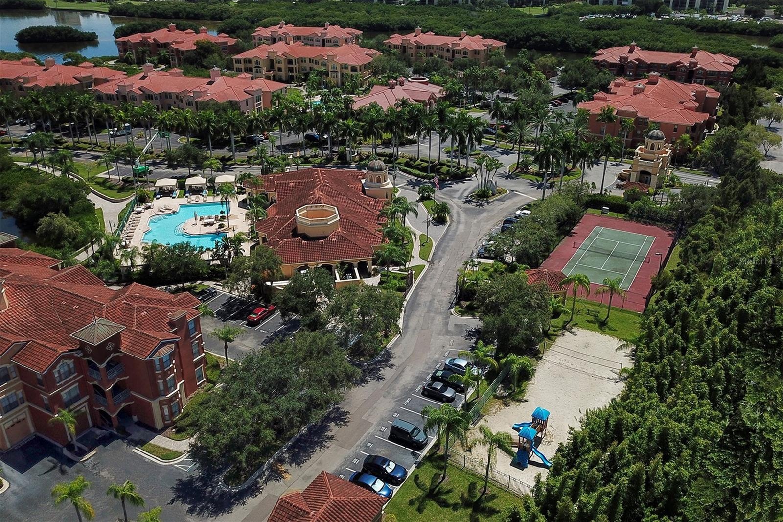 Aerial view of the clubhouse and pool to the left; playground, sand volleyball and tennis court to the right and the "Guardhouse" in the distance poas