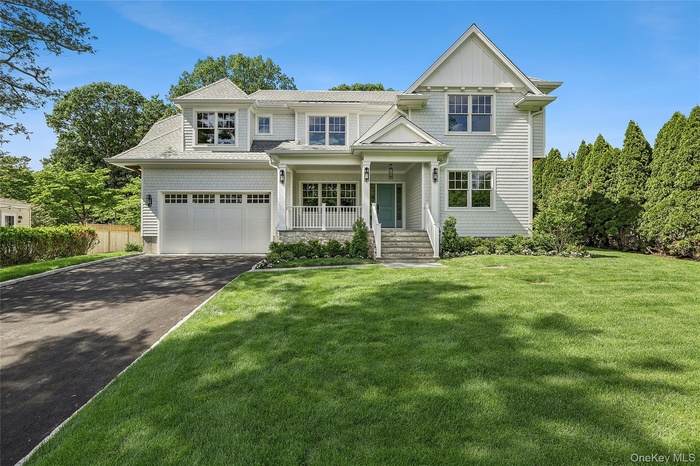 Contemporary Colonial residence featuring a prominent gabled roofline, light-toned siding, and a two-car garage