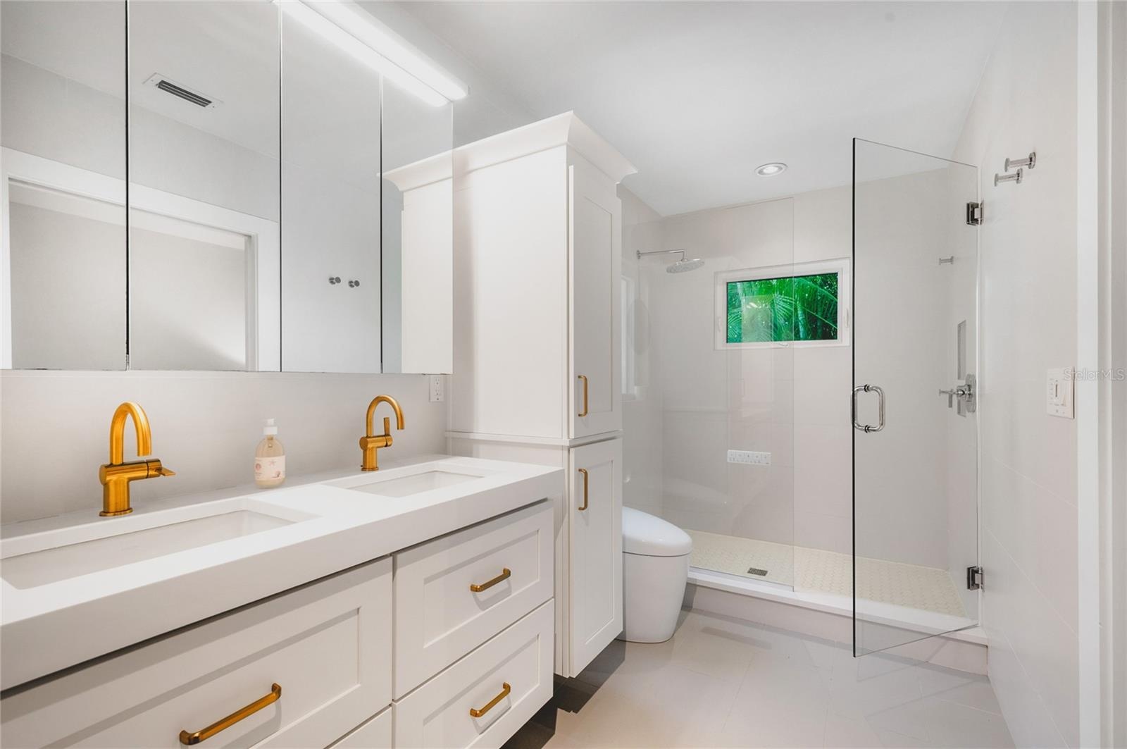 Primary ensuite bathroom with custom cabinetry, dual sinks, high end fixtures and toilet and beautifully tiled shower