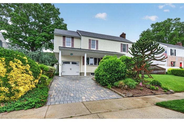 Two-story residence featuring light-colored siding, contrasting shutters, and a covered entryway