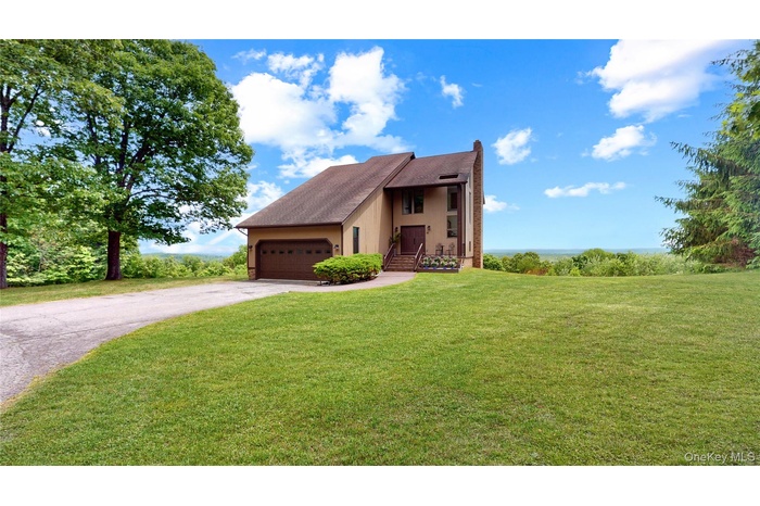 Contemporary-style residence featuring a two-car garage, mature landscaping, and a paved driveway