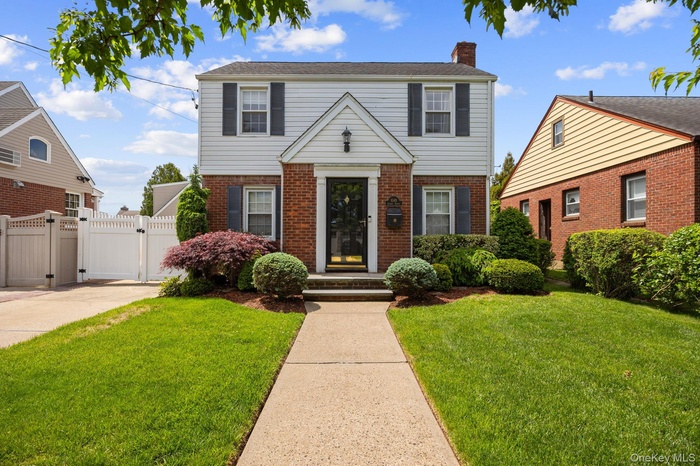 Two-story residence featuring a brick and siding facade, black window shutters, and a central entryway.