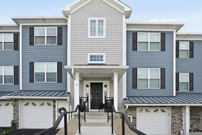 Townhome exterior featuring varied siding materials, stone accents, and a covered entry porch