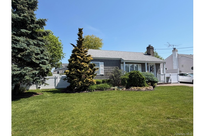Shingle-sided residence featuring a covered front porch with white PVC railings, and a gray shingle roof. Beautifully manicured landscape.