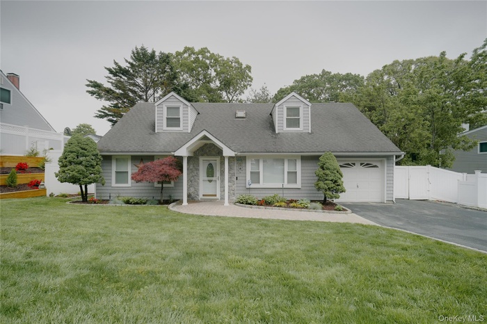 Vinyl Gray siding exterior with dormer windows, an integrated garage, and a large paved driveway