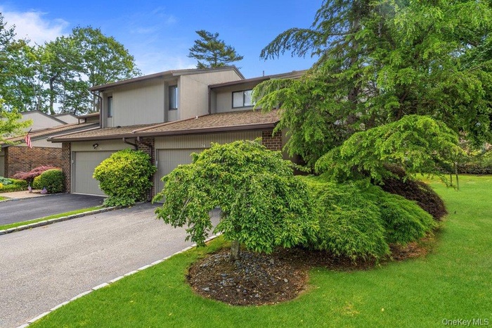 Exterior featuring a sloped roofline, attached garage, and a paved driveway