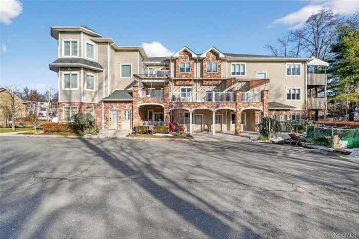 View of front of property featuring a balcony and stone siding