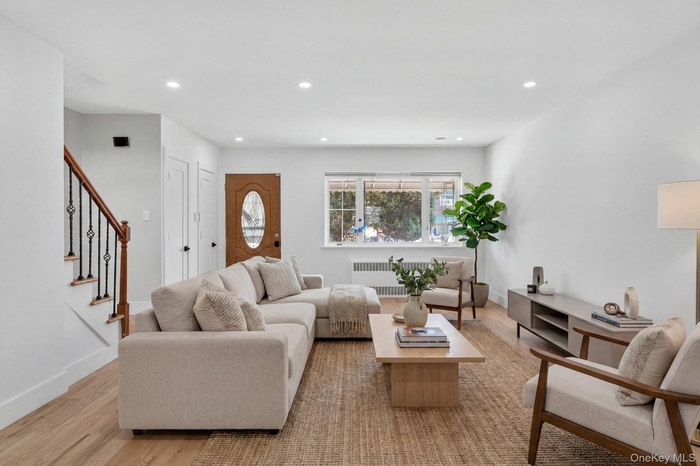 Light-filled living area featuring wood-finish flooring, recessed lighting, and a prominent front entry door with an oval glass insert