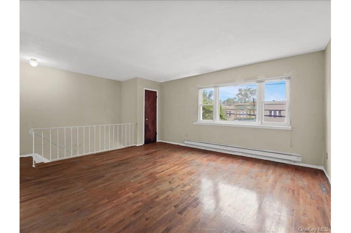 2nd floor Living Room featuring hardwood flooring, a large window, a dark wood-finish, closet, and a white balustrade