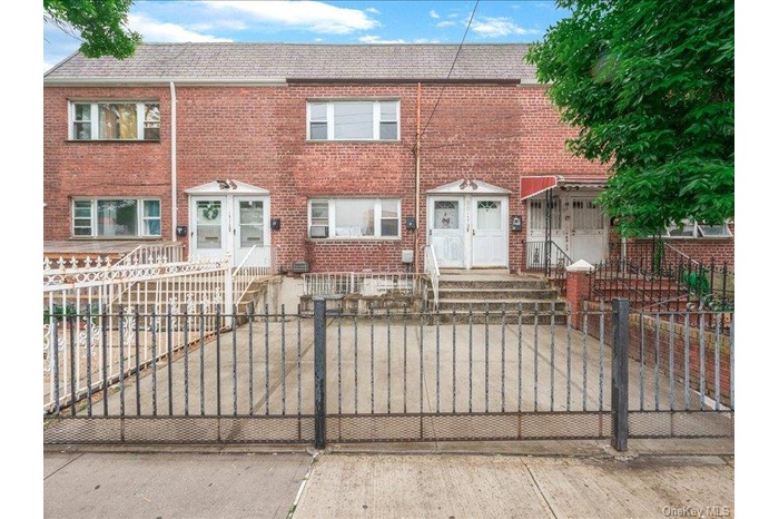 Brick facade featuring multiple entryways and a paved front yard.