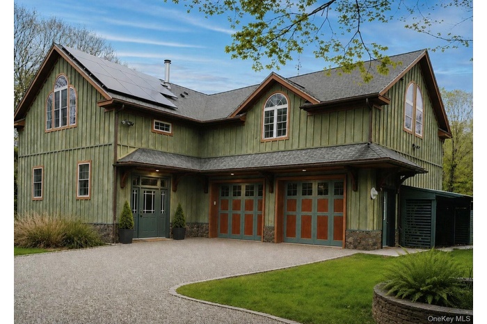 Vertical wood siding exterior with stone foundation detailing, featuring a two-car garage with teal and orange paneled doors