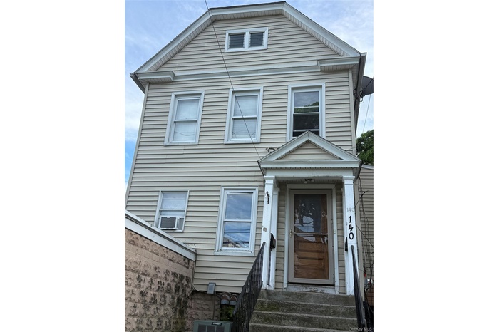 Three-story exterior featuring tan siding and multiple windows