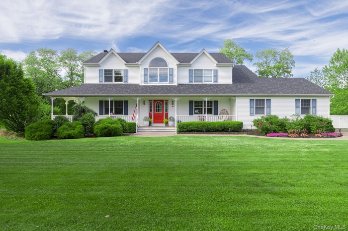 Stunning curb appeal featuring a classic white exterior, a prominent red front door, a covered porch, and beautiful dormer accents."