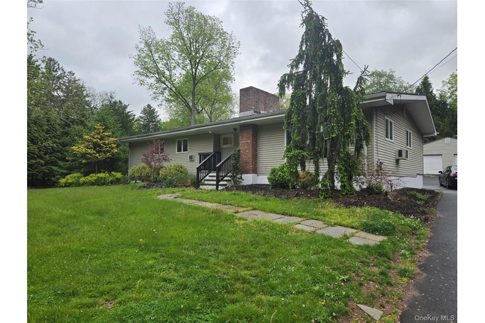 Siding exterior with brick chimney accent and mature landscaping