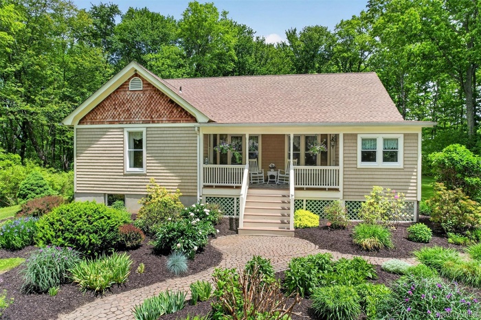 Bungalow-style home featuring light tan siding, a front porch, and a shingled roof