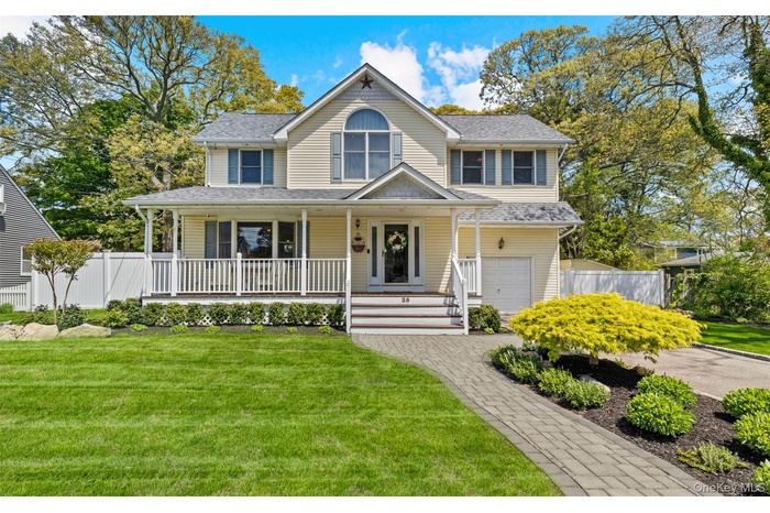Two-story residence featuring light yellow siding, a covered front porch with white railing, and a paver walkway