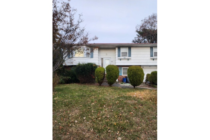 Raised ranch featuring a front yard and brick siding
