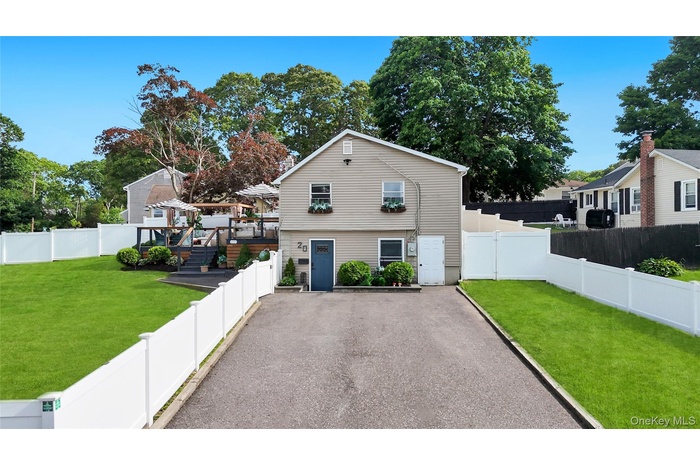Vinyl-sided residence featuring a multi-level rear deck, a paved driveway, and white privacy fencing