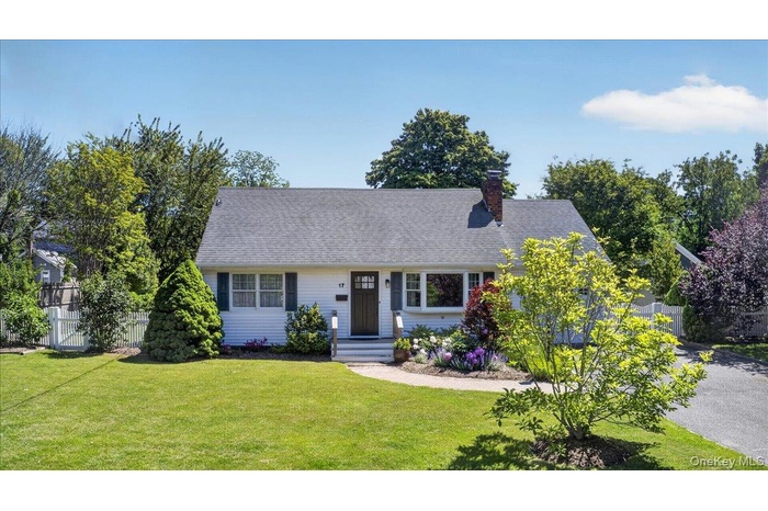 White exterior residence featuring a dark wood front door, front gable roof, and a brick chimney