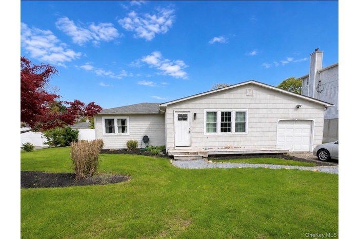 Ranch-style residence featuring light-colored siding, a front entry with a small porch, an attached garage, and a manicured lawn