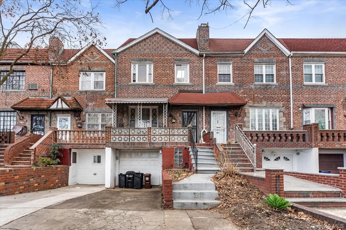 Townhome / multi-family property featuring a garage, concrete driveway, brick siding, and a chimney