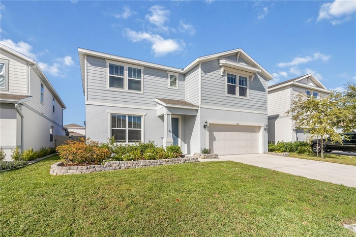 Impressive front view features a long driveway, manicured lawn, and neat flower beds.