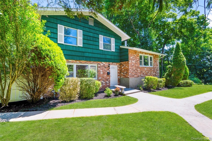 Split-level residence featuring a brick and green siding exterior