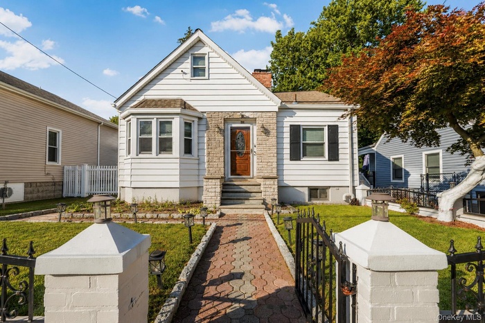 Charming facade featuring white siding, a bay window with multiple panes, and a prominent stone entryway