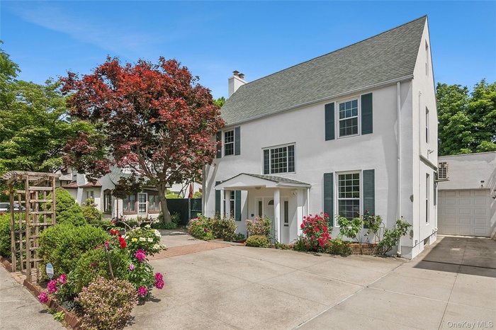White stucco exterior with a prominent gabled roofline and dark green window shutters